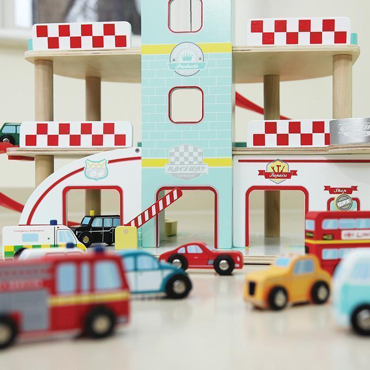 A wooden toy fire station with cars and trucks.
