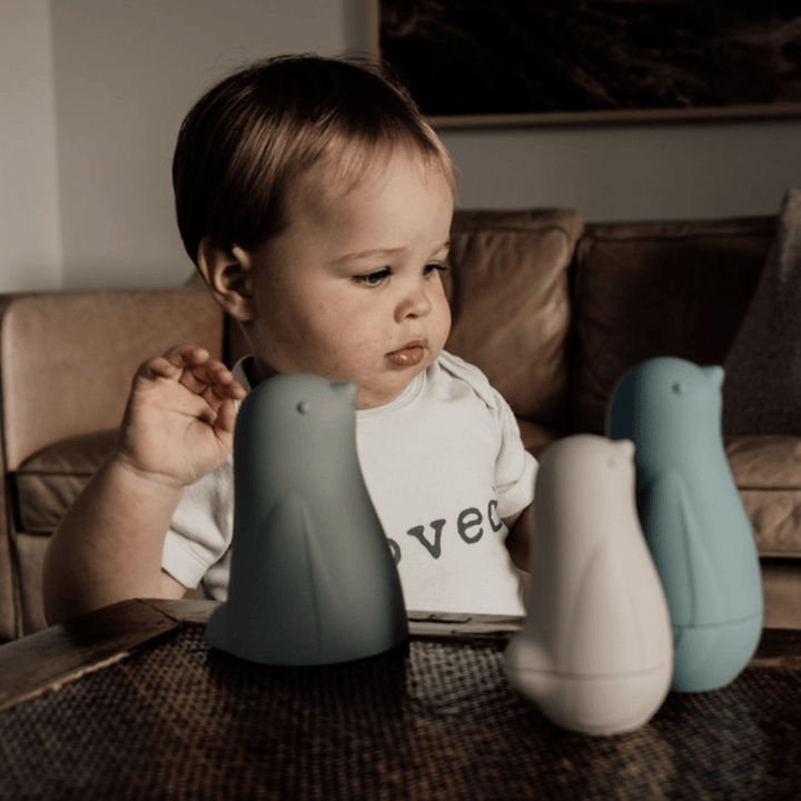 A baby is playing with some Classical Child Silicone Stacking Dolls on a table.