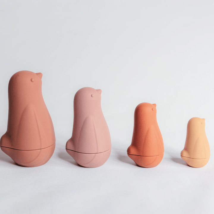 A group of durable Classical Child Silicone Stacking Dolls are lined up on a white surface.