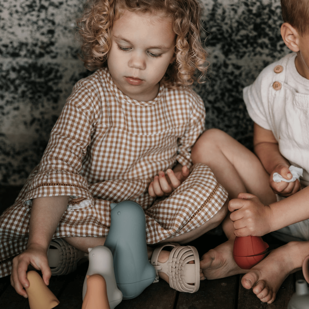 Two children playing with durable Classical Child Silicone Stacking Dolls on the floor.