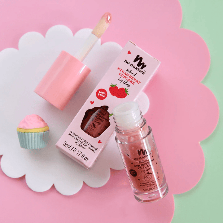 No Nasties All-Natural Kids Lip Gloss and cupcake on a pink background. Perfect combination of fruity and sweet, our No Nasties All-Natural Kids Lip Gloss (Multiple Variants) not only enhances your pout with a glossy shine but also leaves a deliciously