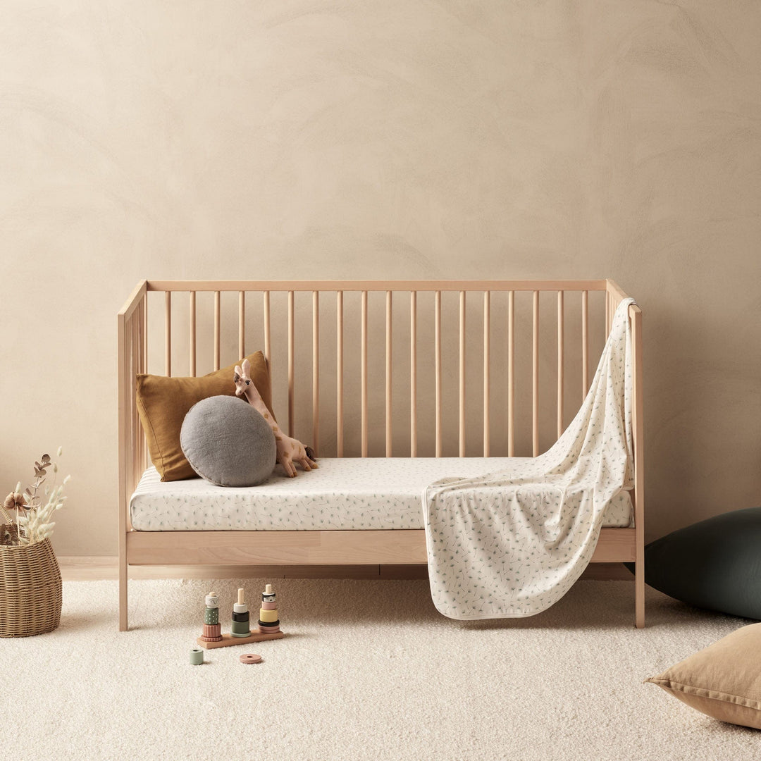 A luxury baby's room with a beige crib, organic pillows, and a Wilson & Frenchy Organic Baby Swaddle Blanket.