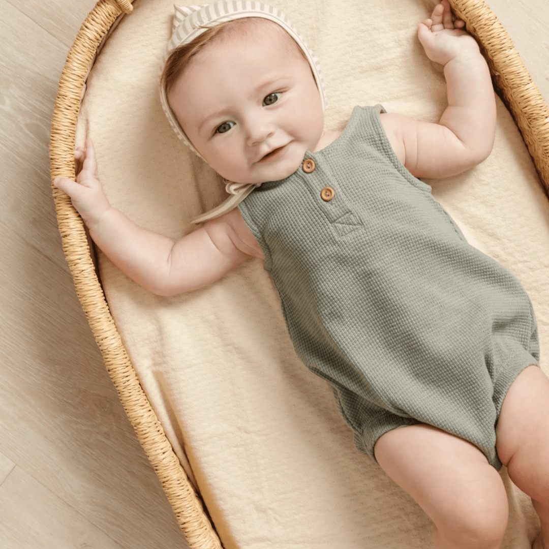Baby-Laying-in-Moses-Basket-Wearing-Quincy-Mae-Organic-Waffle-Sleeveless-Bubble-Romper-Spruce-Naked-Baby-Eco-Boutique
