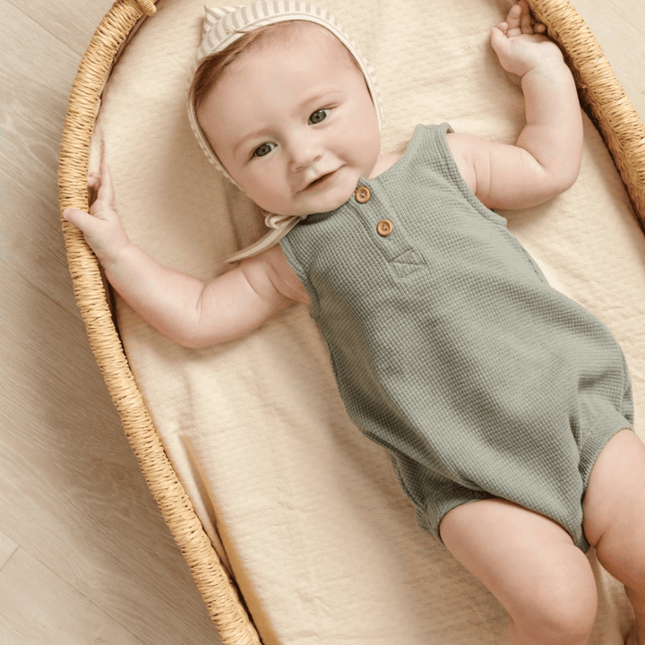 Baby-Laying-in-Moses-Basket-Wearing-Quincy-Mae-Organic-Waffle-Sleeveless-Bubble-Romper-Spruce-Naked-Baby-Eco-Boutique