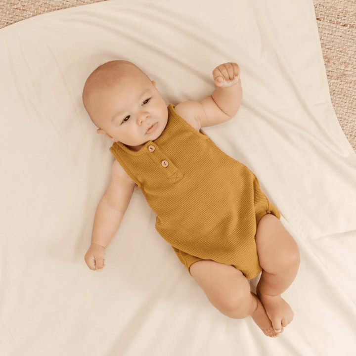 Baby-Laying-on-Blanket-Wearing-Quincy-Mae-Organic-Waffle-Sleeveless-Bubble-Romper-Ochre-Naked-Baby-Eco-Boutique