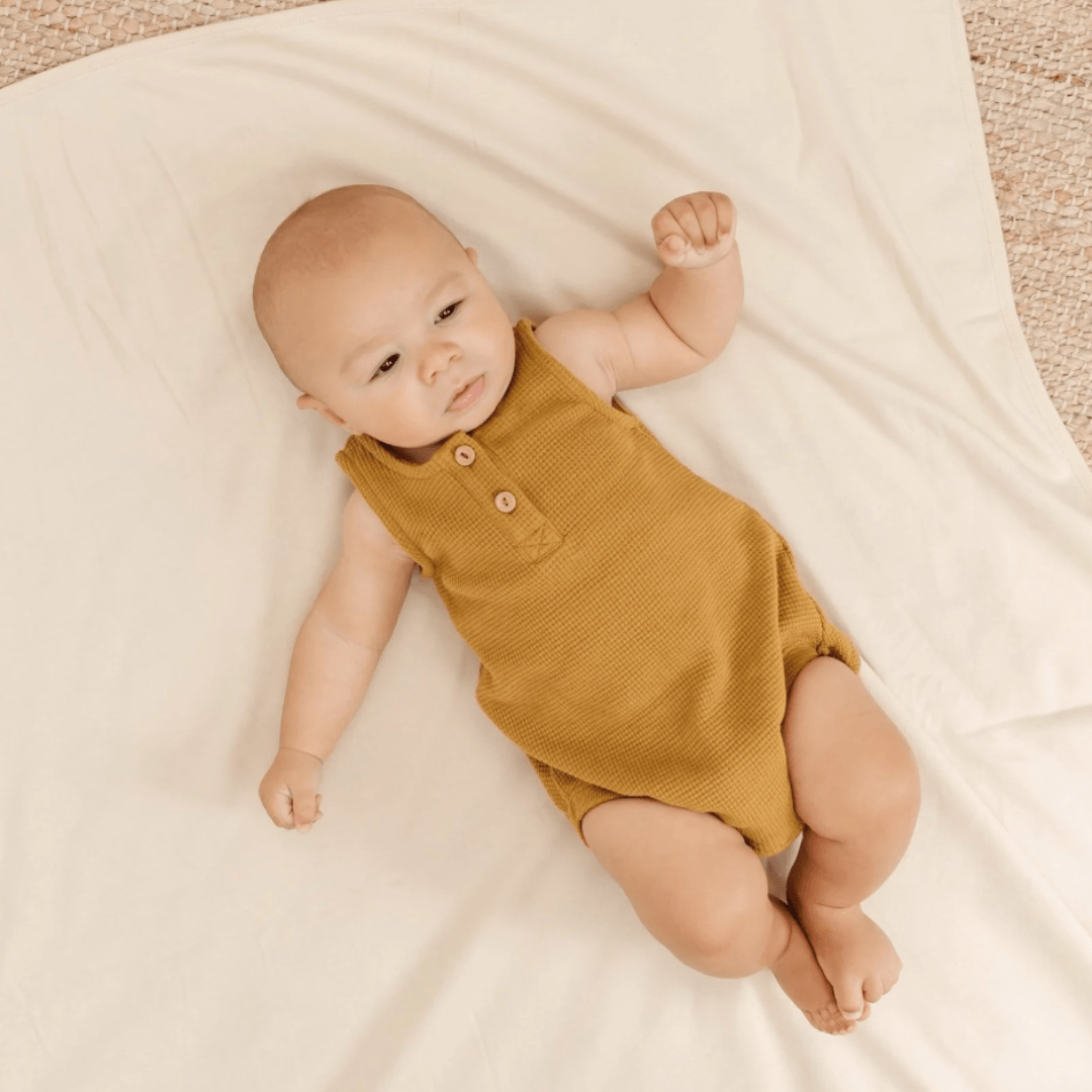 Baby-Laying-on-Blanket-Wearing-Quincy-Mae-Organic-Waffle-Sleeveless-Bubble-Romper-Ochre-Naked-Baby-Eco-Boutiqu