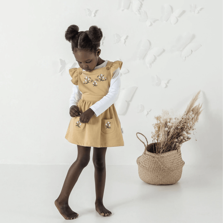 Little-Girl-Wearing-Aster-And-Oak-Organic-Cotton-Embroidered-Pinafore-Dress-Taupe-Floral-Naked-Baby-Eco-Boutique