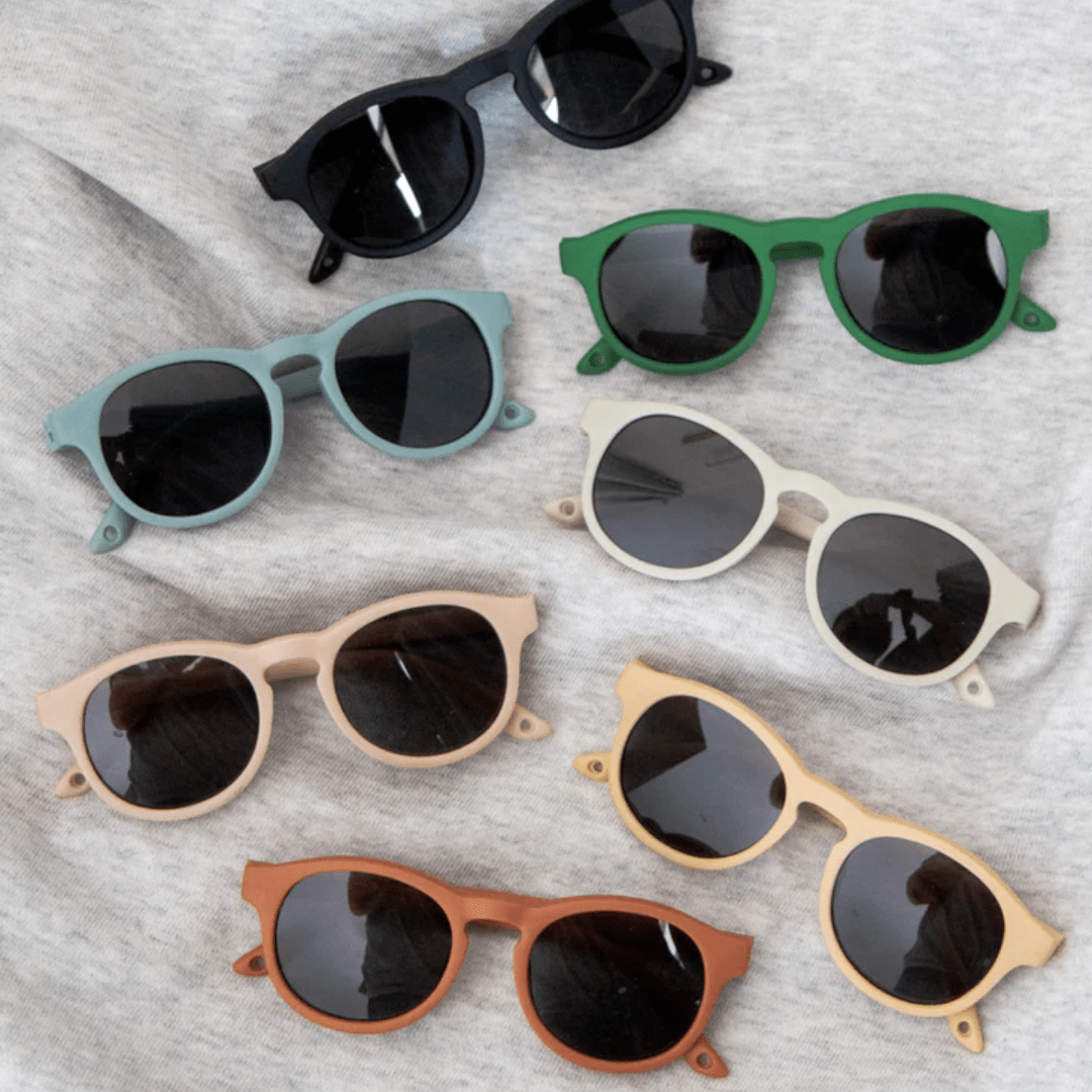 A group of UV400 protected sunglasses in various colors and styles, including the trendy Zazi Shades Baby & Toddler Sunglasses, set against a neutral grey background.
