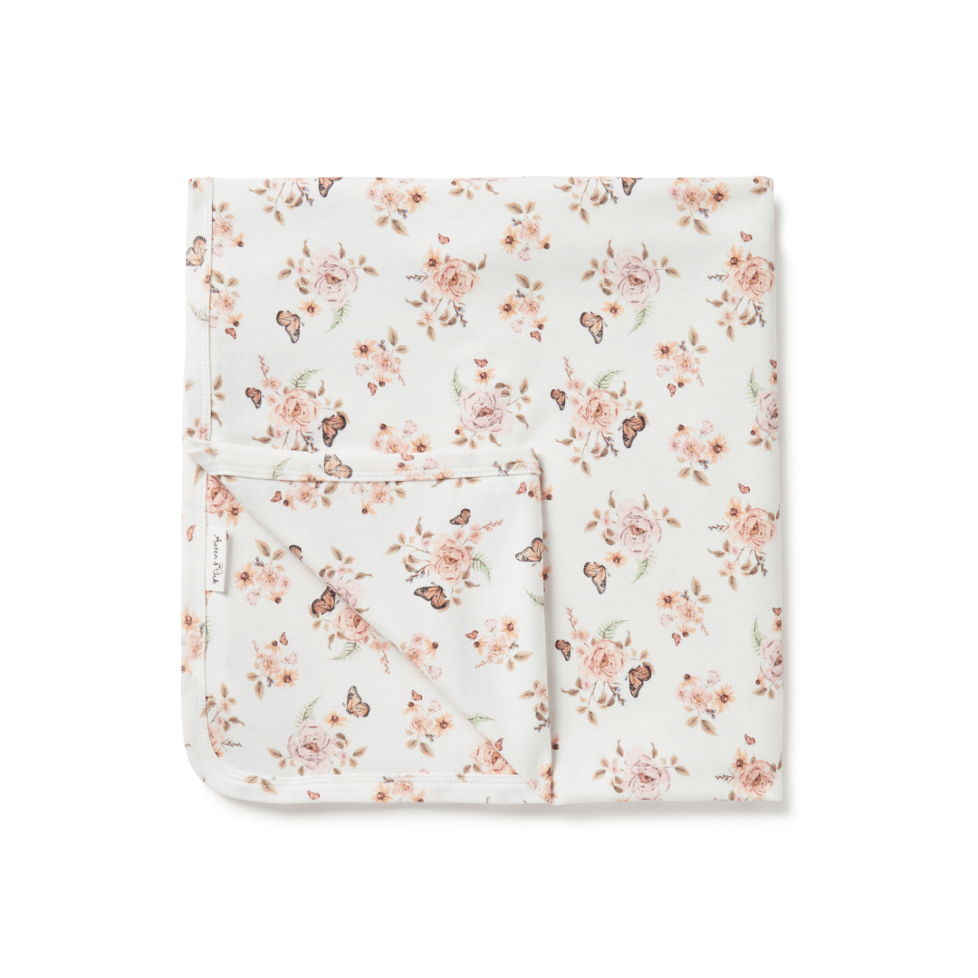 An Aster & Oak organic cotton baby swaddle wrap featuring a hand-illustrated print of pink flowers.