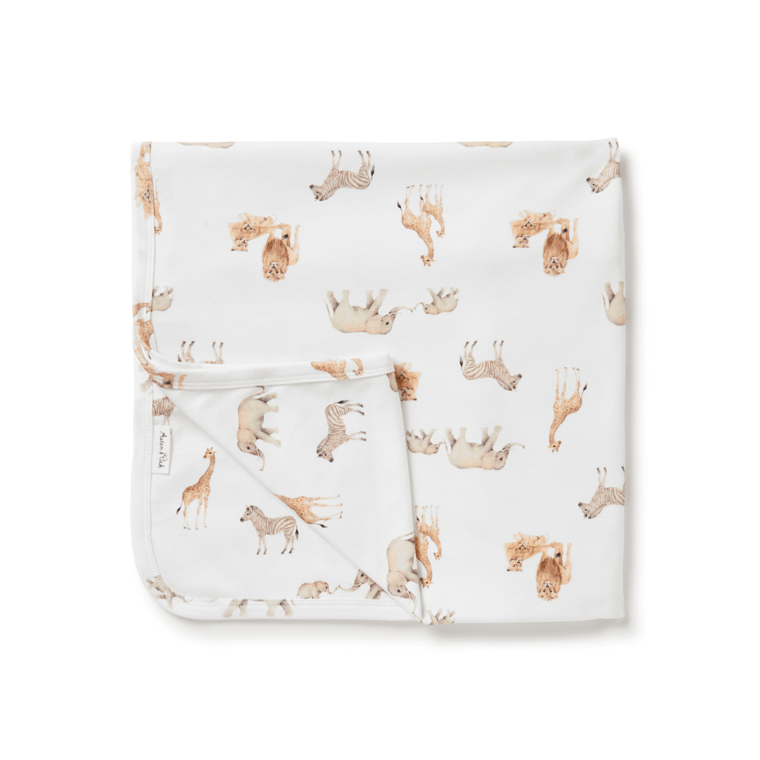 A hand-illustrated Aster & Oak organic cotton baby swaddle wrap with giraffes and elephants print.