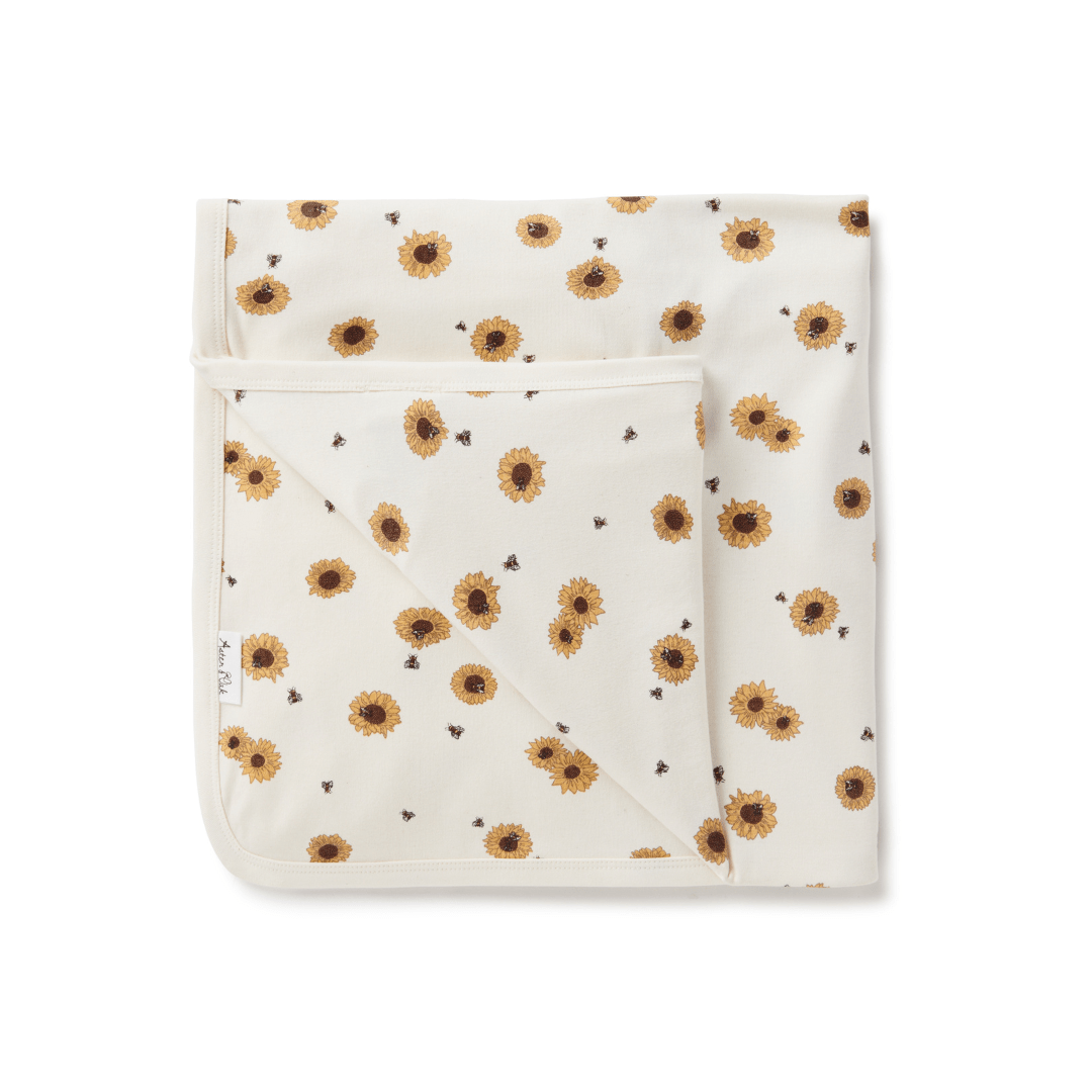 A hand-illustrated print of sunflowers on the Aster & Oak Organic Cotton Baby Swaddle Wrap.