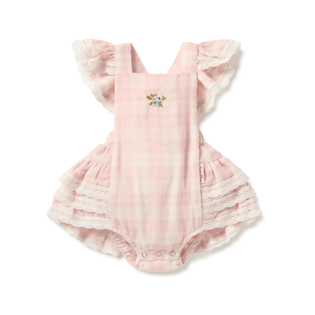 Pink and white gingham baby and toddler playsuit featuring ruffles at the shoulders, legs, and bum, snaps at the crotch, and small floral embroidery at the chest