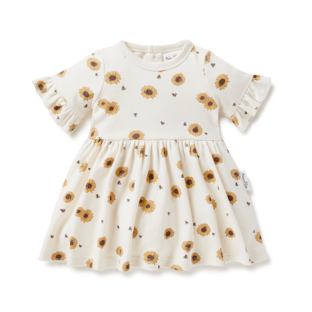 Dress for babies and kids with full skirt, ruffle sleeves, and bright yellow sunflowers on an off-white background