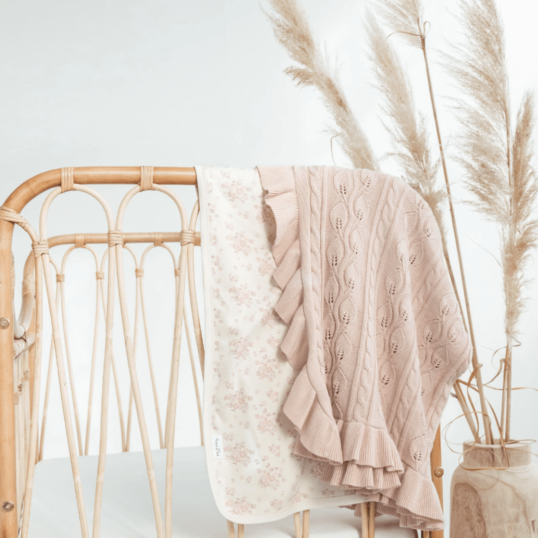 Aster-and-Oak-Organic-Ruffle-Cable-Knit-Baby-Blanket-Blush-Draped-Over-Cot-with-Floral-Swaddle-Naked-Baby-Eco-Boutique