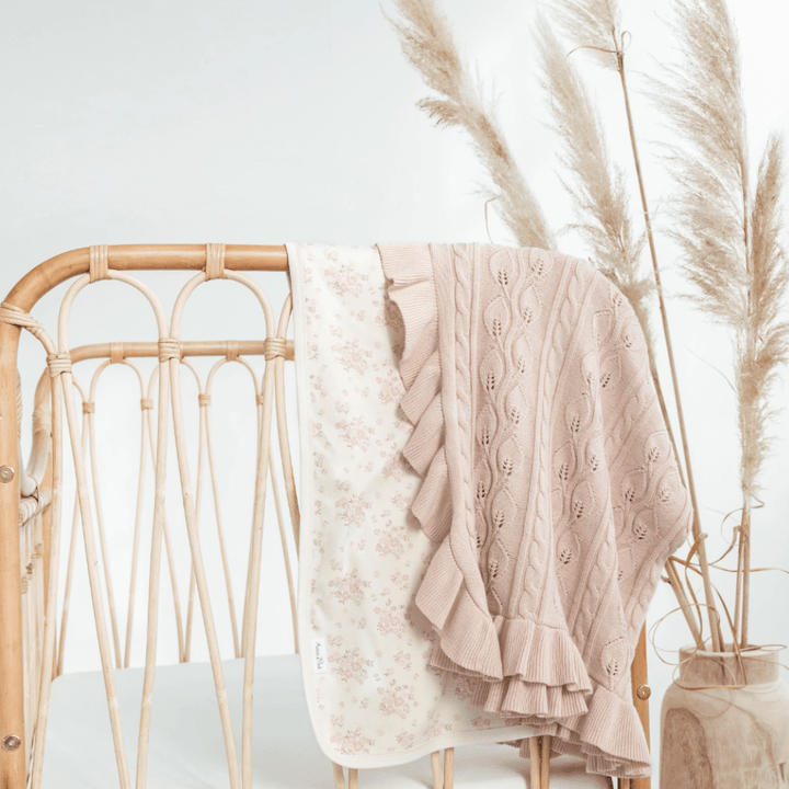 Aster-and-Oak-Organic-Ruffle-Cable-Knit-Baby-Blanket-Blush-Draped-Over-Cot-with-Floral-Swaddle-Naked-Baby-Eco-Boutique