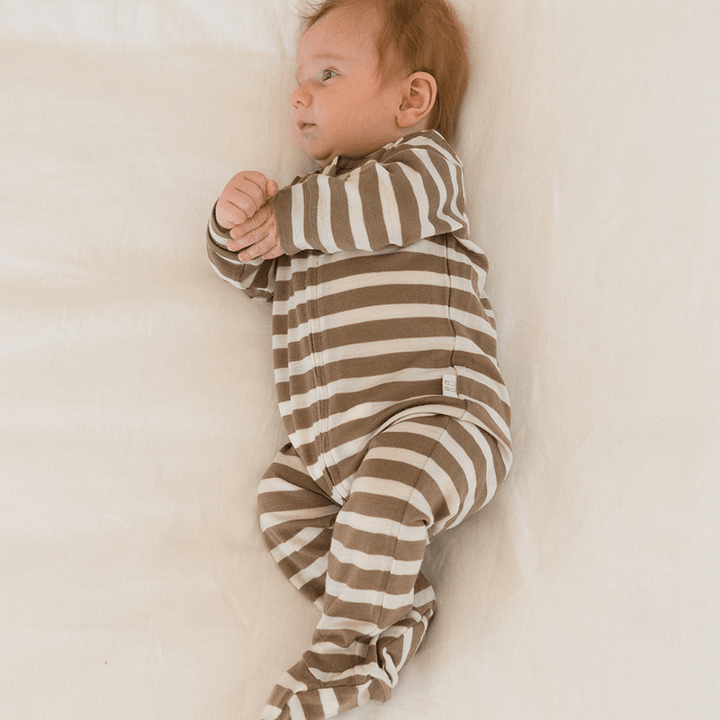 Baby-Laying-on-Side-Wearing-Babu-Merino-Growsuit-with-Feet-Walnut-Stripe-Naked-Baby-Eco-Boutique