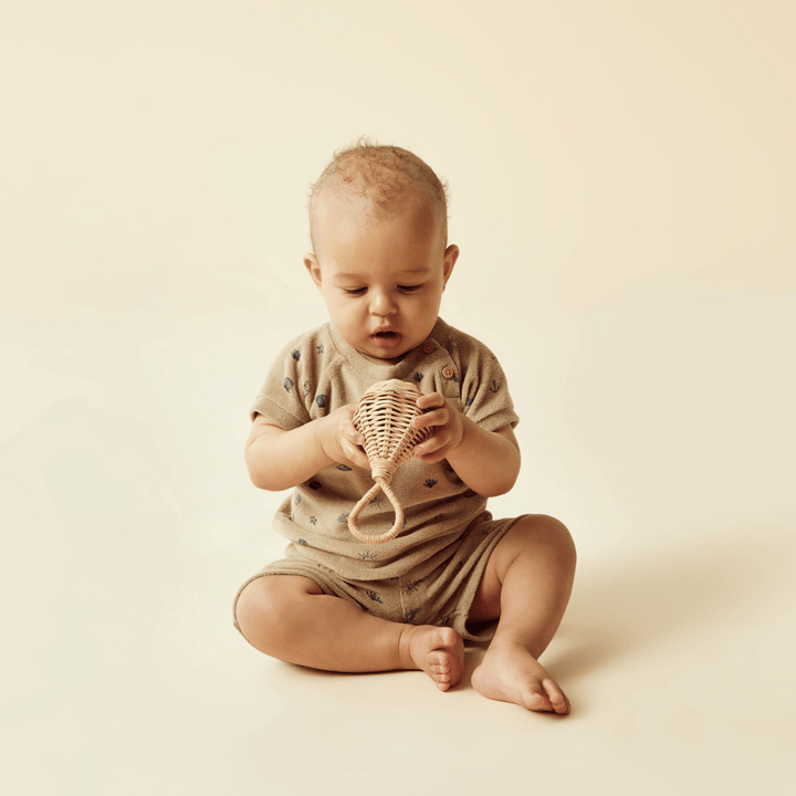 A Wilson & Frenchy baby playing with a toy on a white background, wearing a Wilson & Frenchy Organic Terry Sweat Top made of 100% organic cotton.