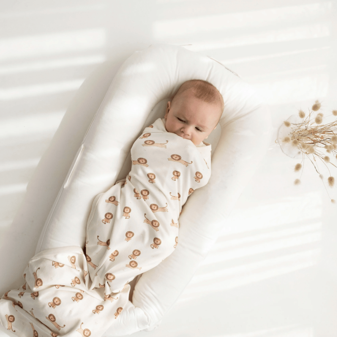 A baby peacefully sleeping in an Aster & Oak Organic Cotton Baby Swaddle Wrap.