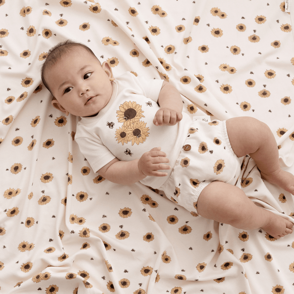 Baby-With-Sunflower-Swaddle-Wearing-Aster-And-Oak-Organic-Cotton-Print-Top-Sunflower-Naked-Baby-Eco-Boutique