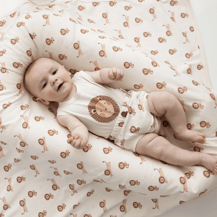 An Aster & Oak Organic Cotton Baby Swaddle Wrap with a hand-illustrated lion print, made from soft organic cotton.
