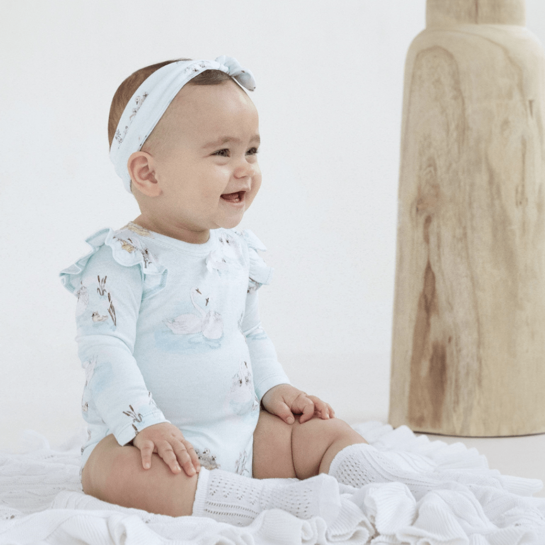 Baby-in-Onesie-Sitting-on-Aster-and-Oak-Organic-Ruffle-Cable-Knit-Baby-Blanket-Snow-Naked-Baby-Eco-Boutique