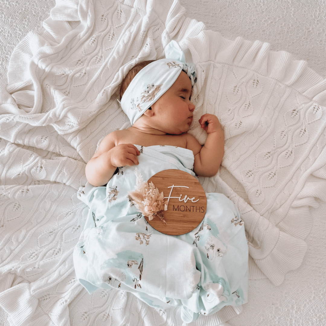Baby-with-Milestone-Plaque-Laying-on-Aster-and-Oak-Organic-Ruffle-Cable-Knit-Baby-Blanket-Snow-Naked-Baby-Eco-Boutique