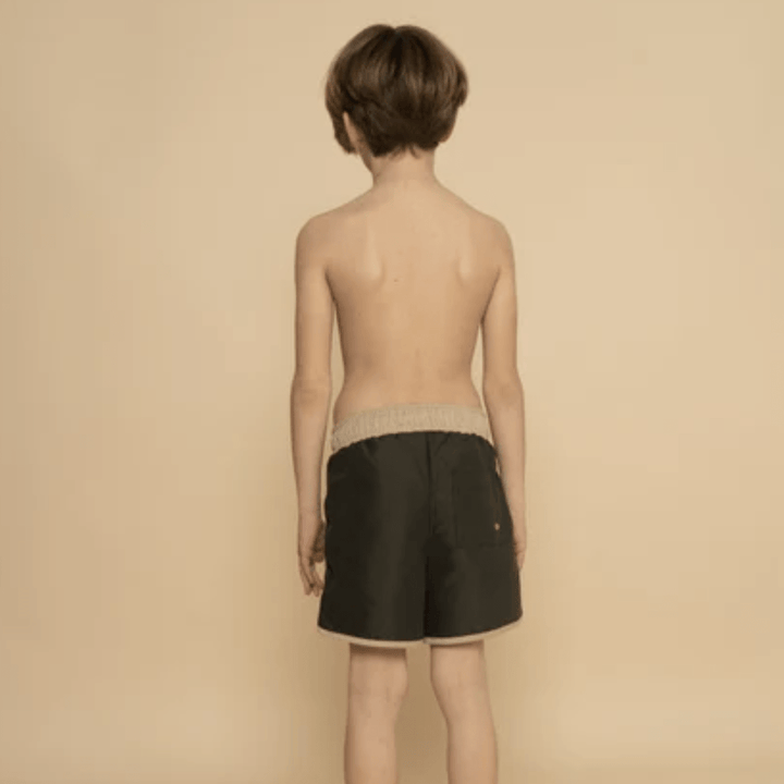 The back of a boy wearing Grech & Co. UPF 40+ Recycled Swim Trunks in black.