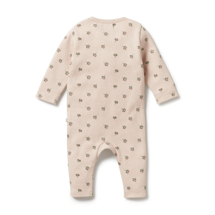 Wilson & Frenchy Beige GOTS-certified organic cotton baby onesie with a pattern of tiny green motifs on a white background.