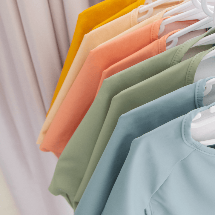 A row of colorful, machine-washable Zazi Recycled Full-Sleeved Bib (Multiple Variants) shirts hanging on a rack.