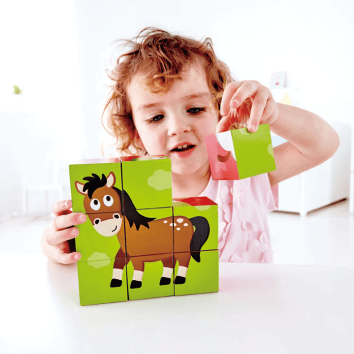 A little girl is playing with a Hape Animal Block Puzzle (Multiple Variants) with a wooden horse on it.