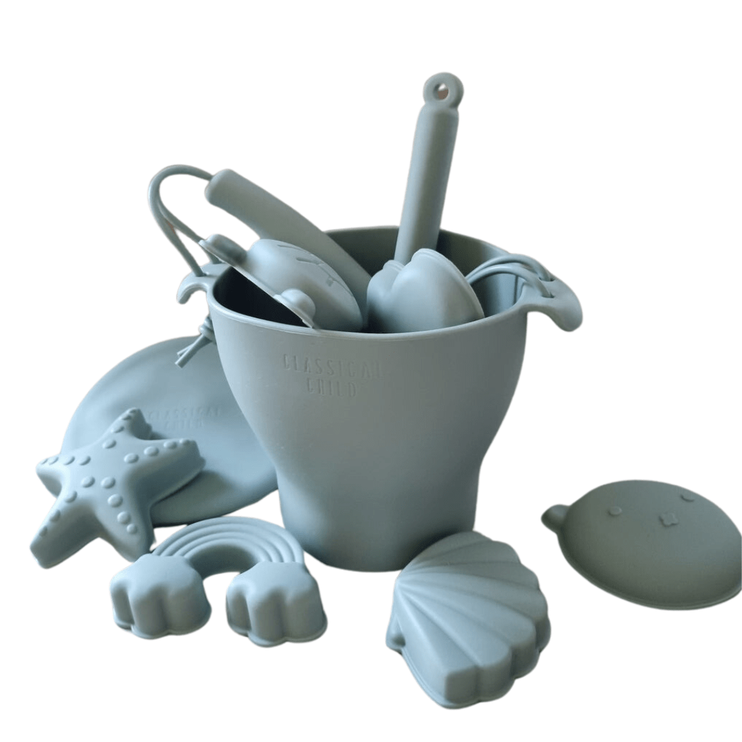 A Classical Child silicone beach bucket set filled with seashells and utensils.