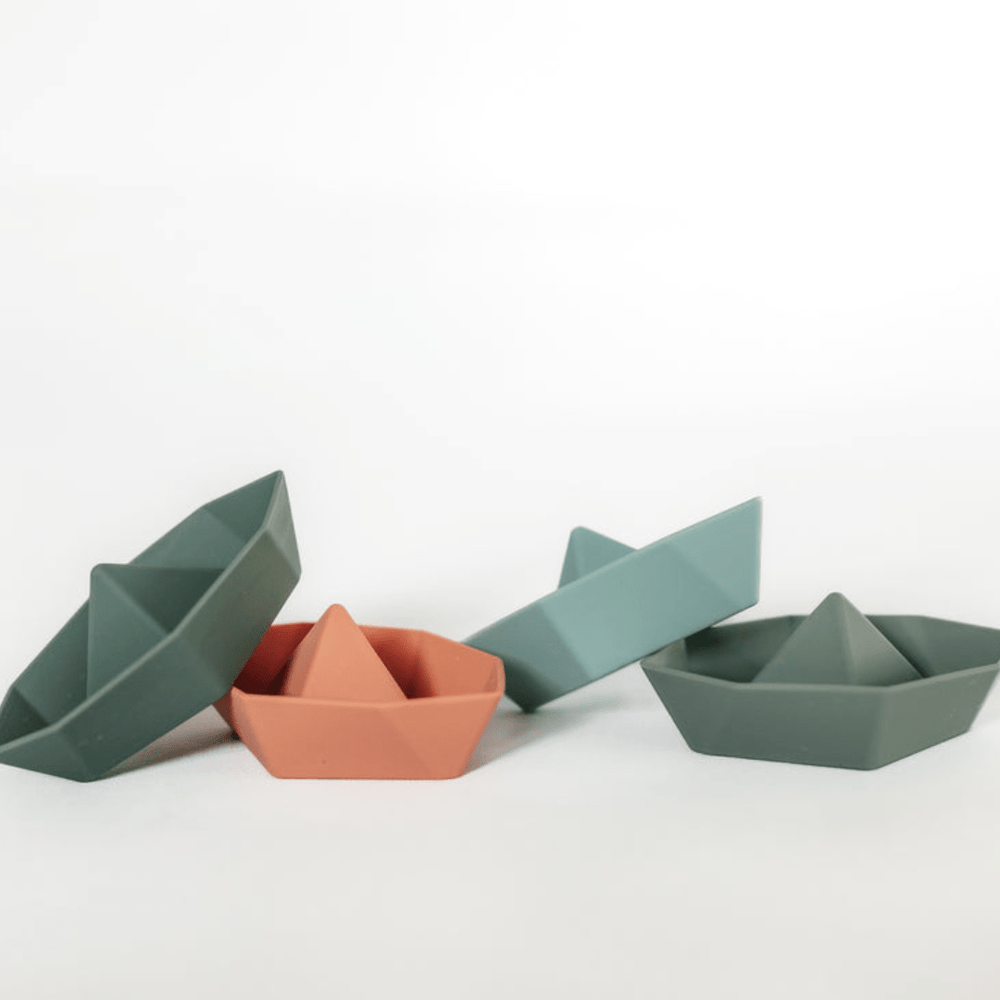 A set of four Classical Child silicone boat-shaped bowls on a white surface.