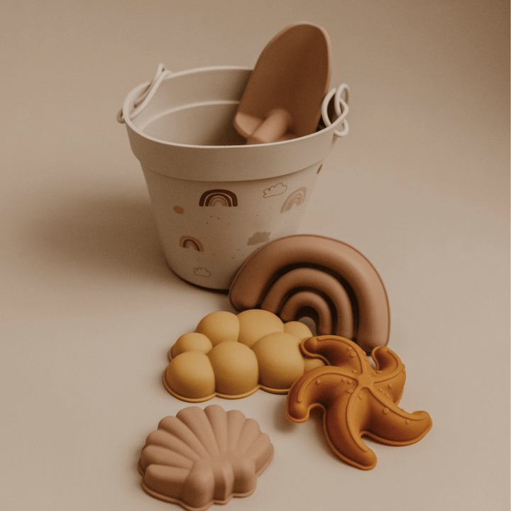A bucket full of Classical Child eco-friendly silicone sand sets, beach toys, shells, and a starfish.