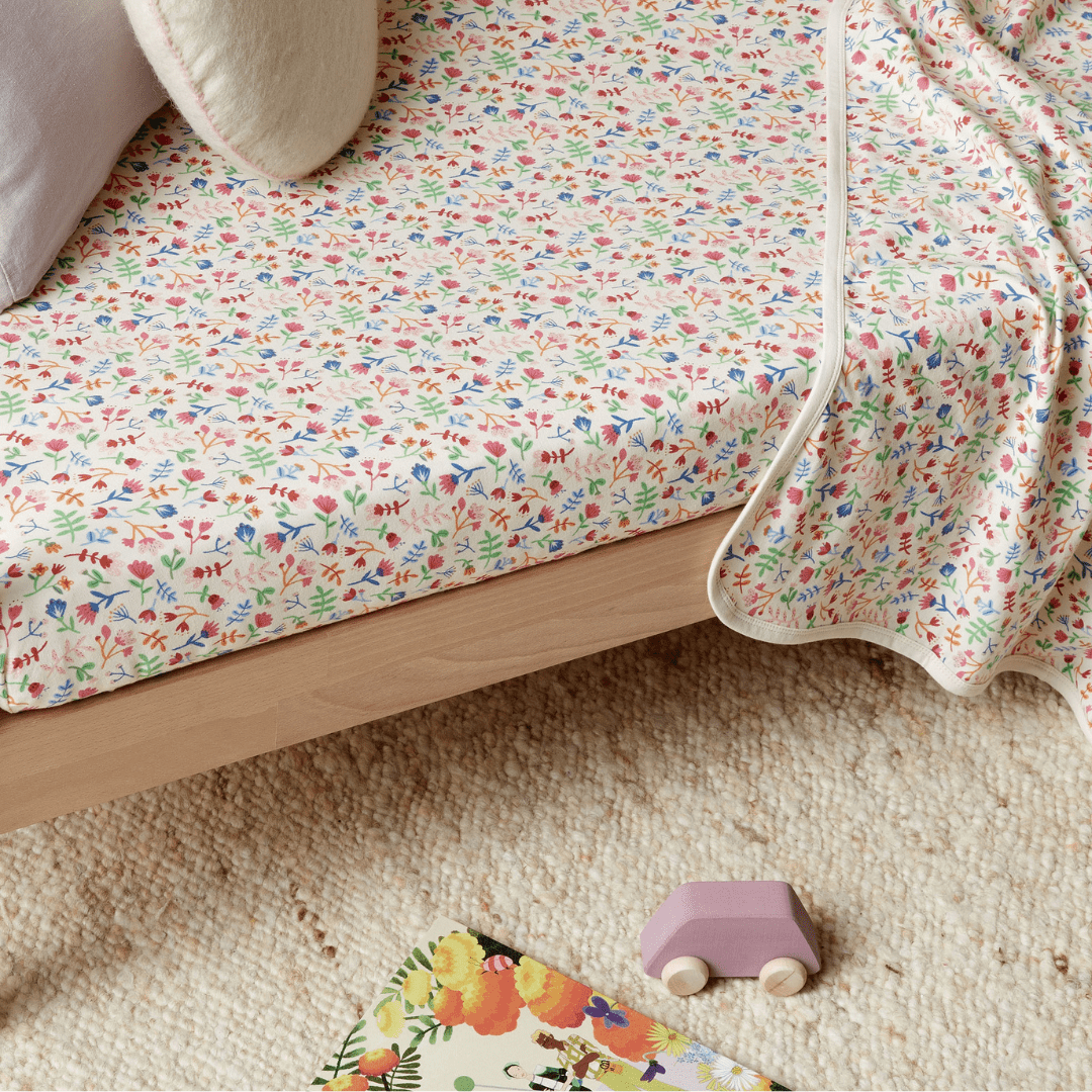 A child's room with a Wilson & Frenchy Organic Cotton Cot Sheet - LUCKY LASTS - FLOAT AWAY ONLY and a toy on it.