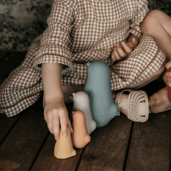 Two children playing with Classical Child Silicone Stacking Dolls on a wooden floor.