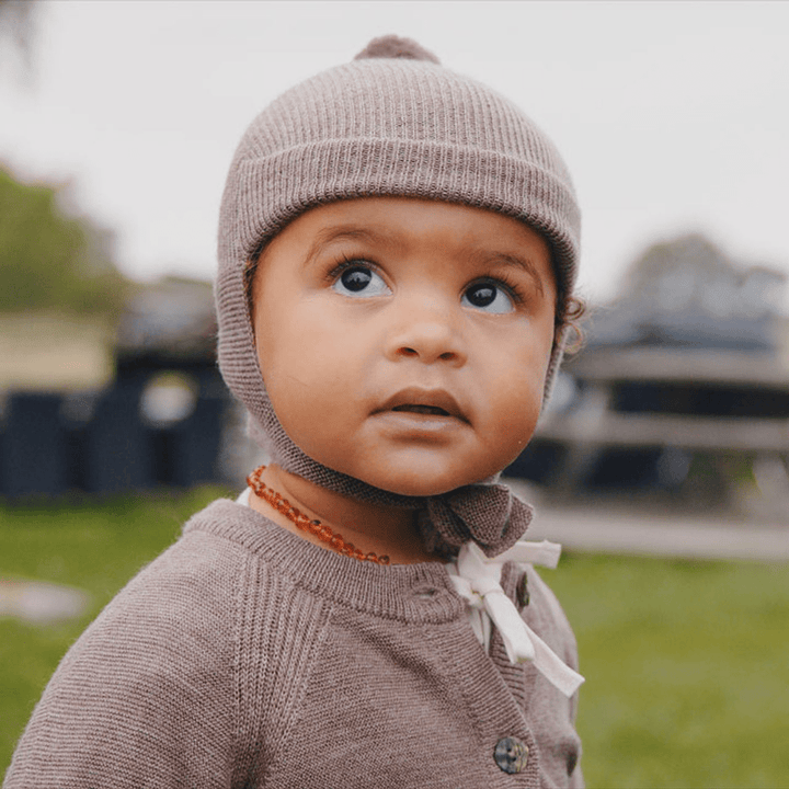 A baby wearing a Saga Copenhagen Merino bonnet and sweater.