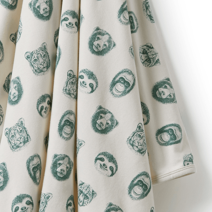 A Wilson & Frenchy luxury organic baby swaddle blanket with green faces on it.