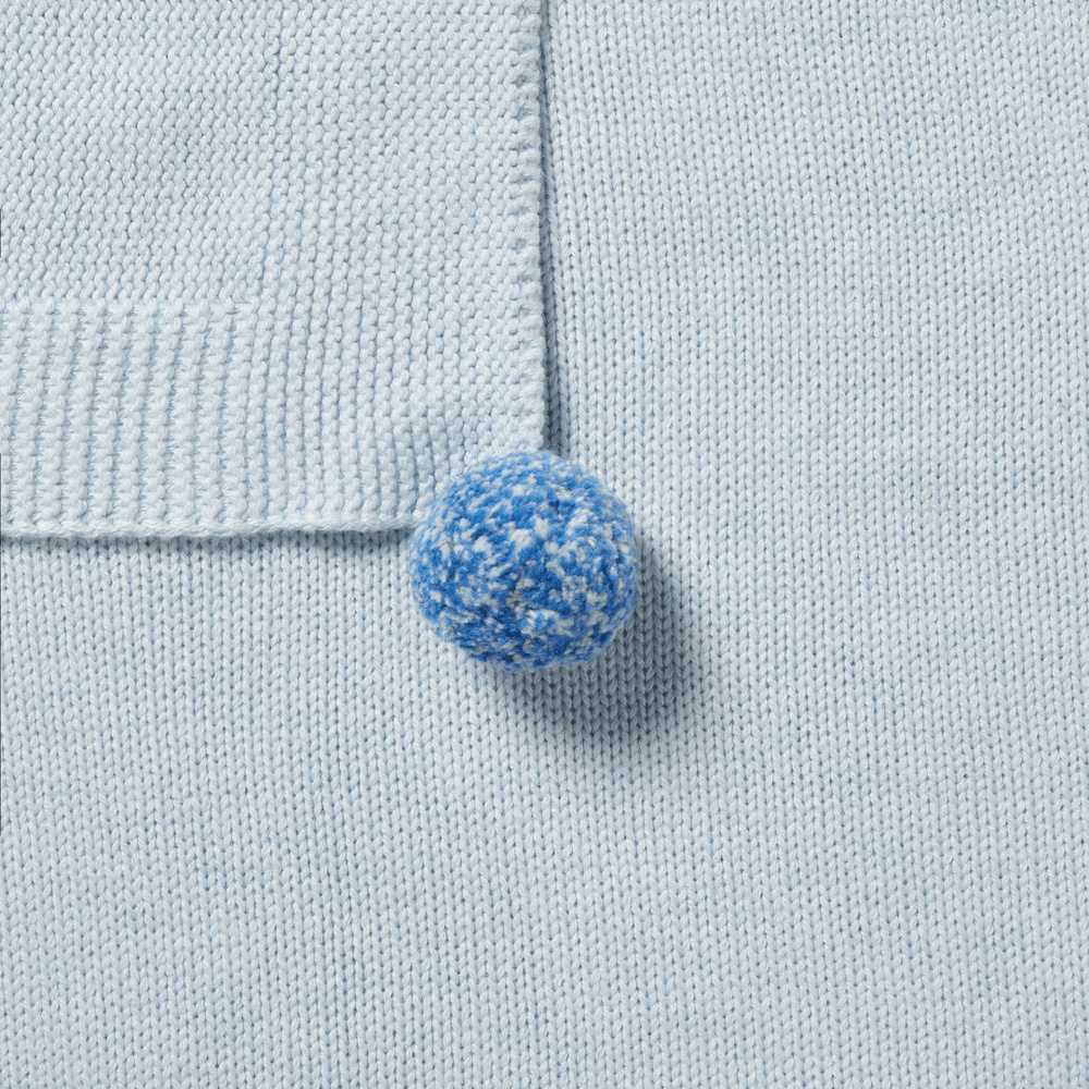 A blue button on a Wilson & Frenchy Knitted Baby Blanket.