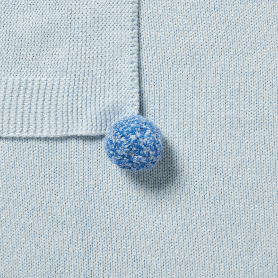 A blue button on a Wilson & Frenchy Knitted Baby Blanket.
