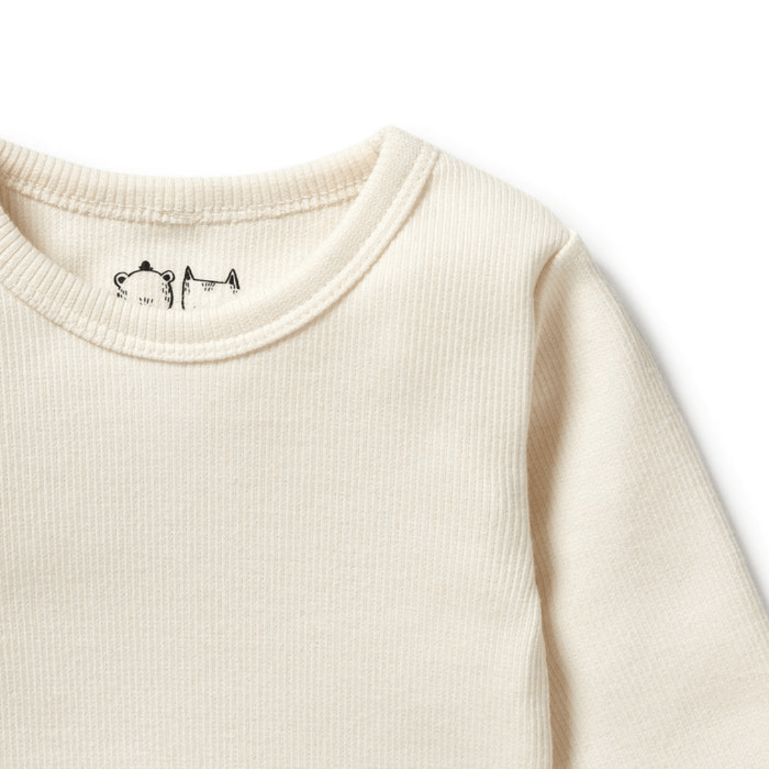 Close-up of a Wilson & Frenchy cream-colored ribbed baby and toddler long-sleeved top with a small embroidered design near the collar.