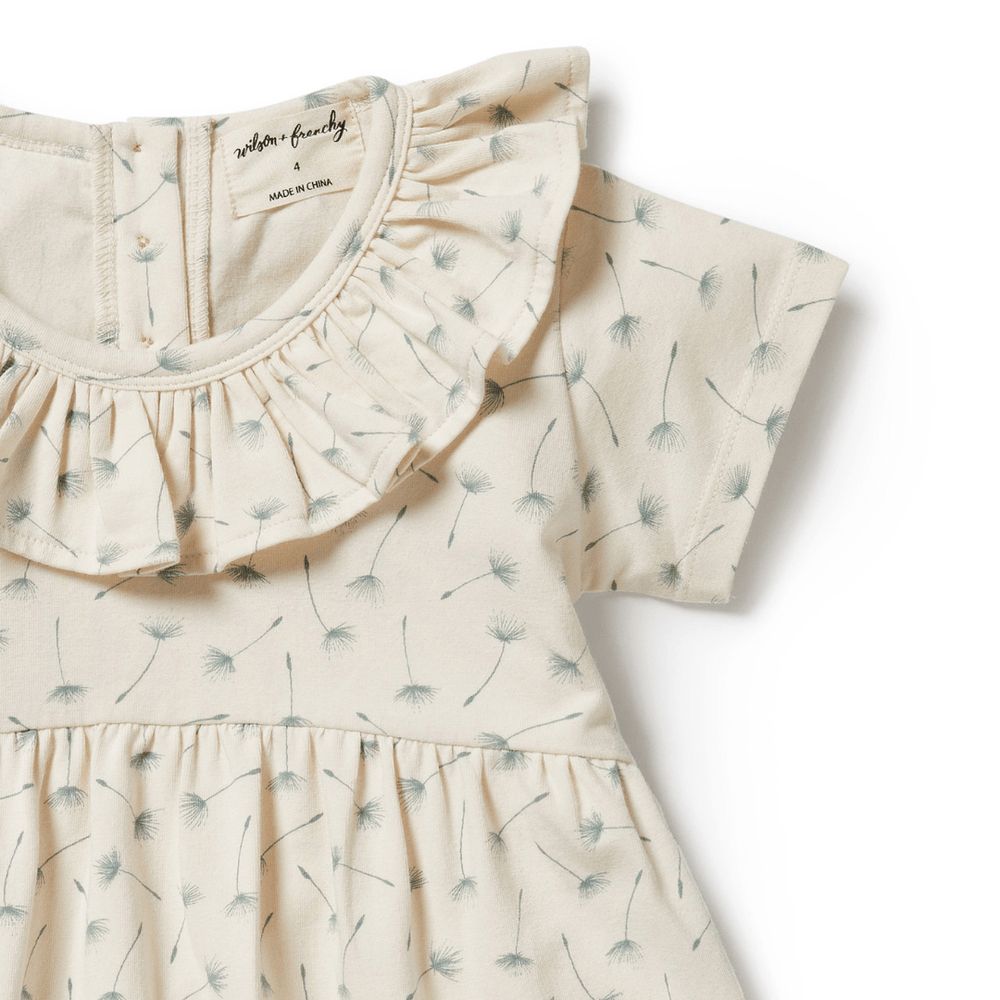 A Wilson & Frenchy Float Away Organic Ruffle Kids Dress with a ruffled ruffle and dandelion print, made of organic cotton.