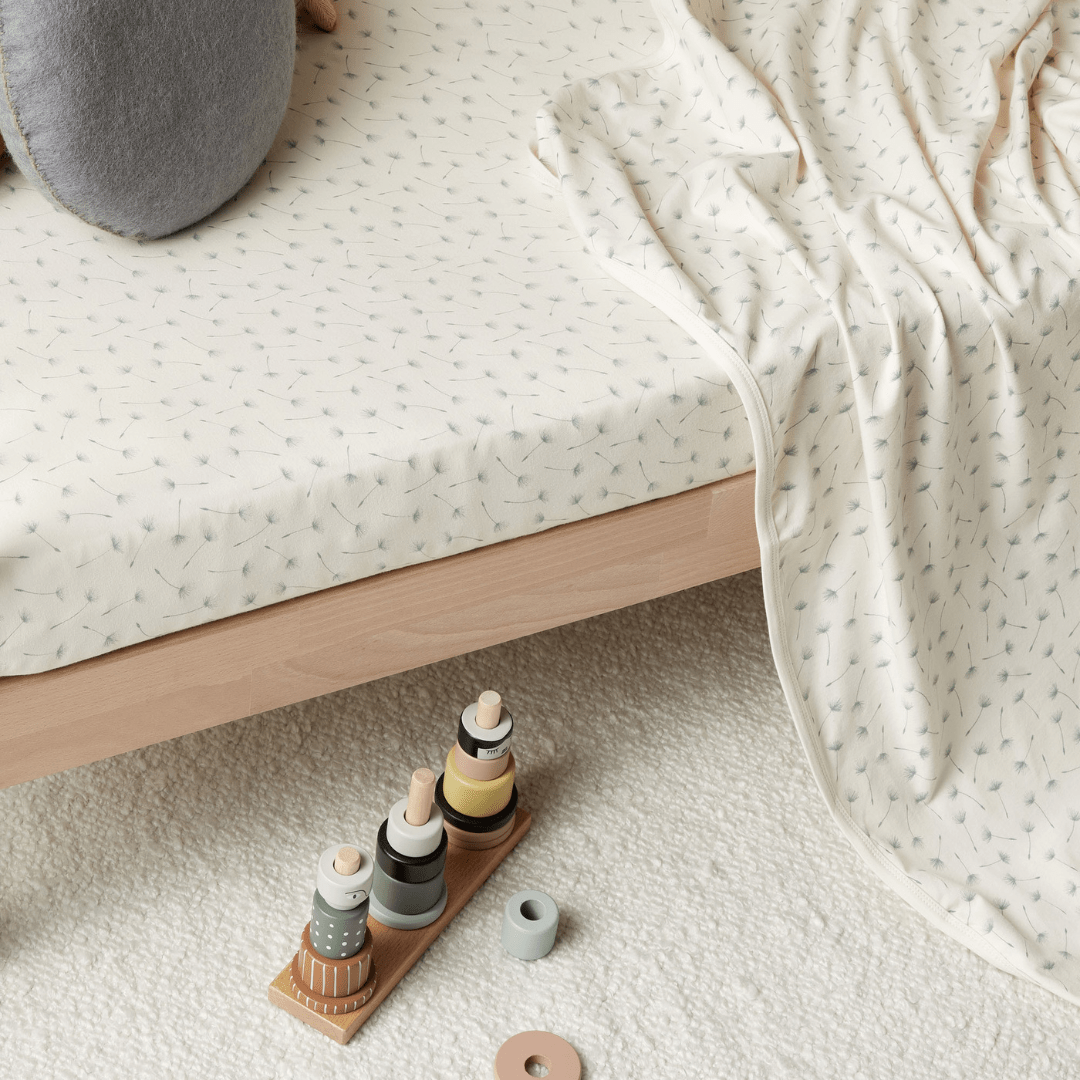 An Wilson & Frenchy Organic Cotton Cot Sheet with a wooden toy - the perfect baby shower present.
