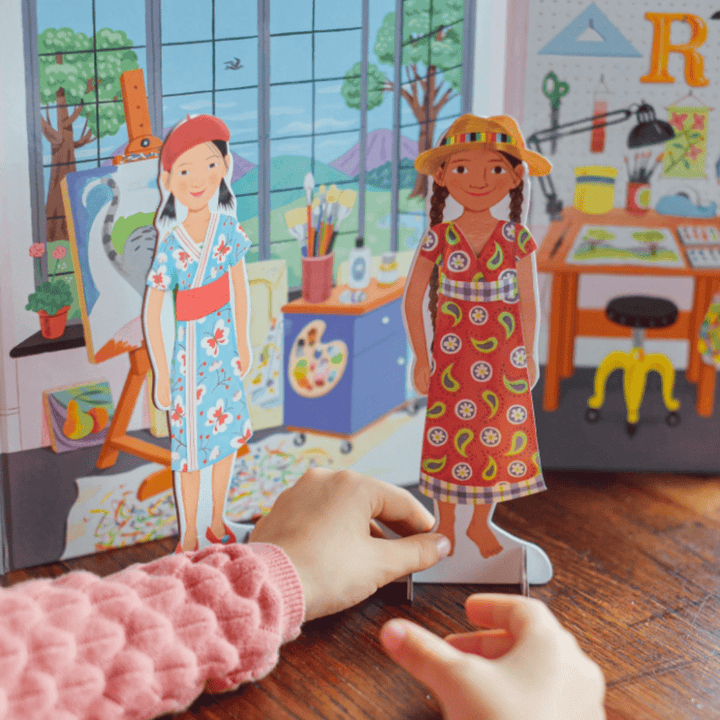 A child engaged in imaginative play with an eeBoo Paper Doll Set on a table.