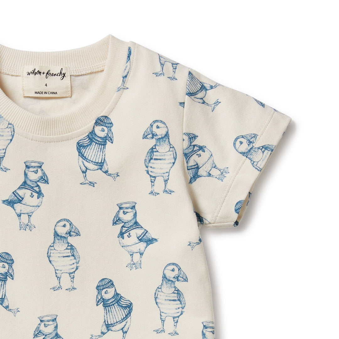 Close-up of a cream-colored, Wilson & Frenchy organic kids tee with a pattern of sketched puffins.