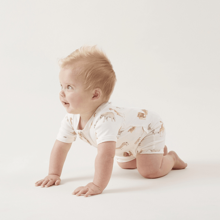 A baby crawling on the floor in a white romper made from Aster & Oak Organic Cotton Zip Romper.