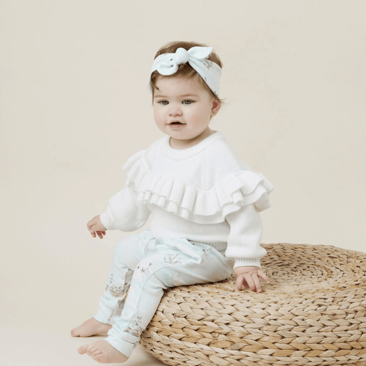 Cute-Little-Girl-Sitting-on-Stool-Wearing-Aster-and-Oak-Organic-Ruffle-Knit-Jumper-Snow-Naked-Baby-Eco-Boutique