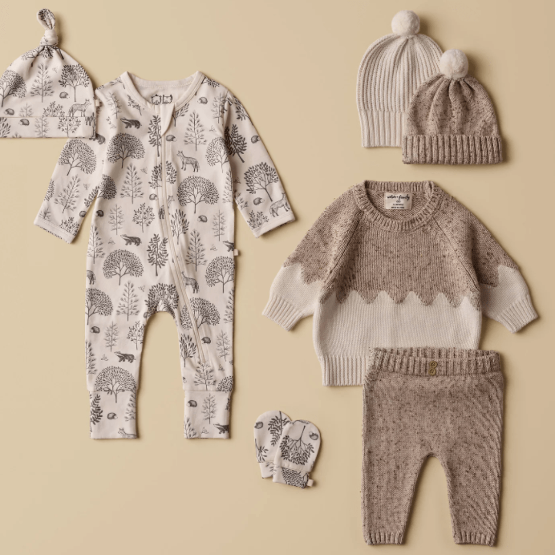 Assortment of Wilson & Frenchy Organic Baby Pyjamas and accessories with nature-inspired patterns displayed on a neutral background.