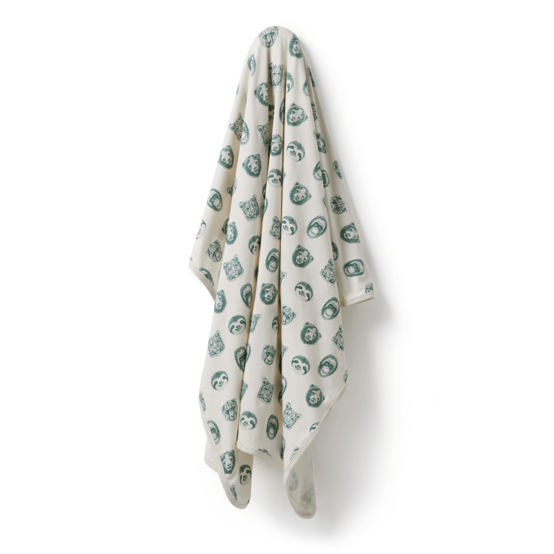 A luxury Wilson & Frenchy Organic Baby Swaddle Blanket in Tropical Garden print with green leaves on it.
