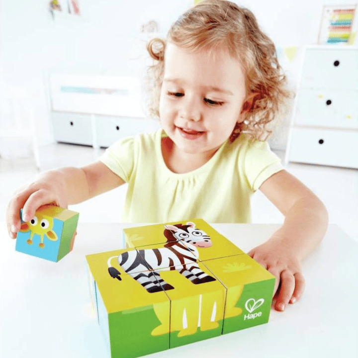 A little girl is playing with a Hape Animal Block Puzzle, featuring farm animals and jungle animals.