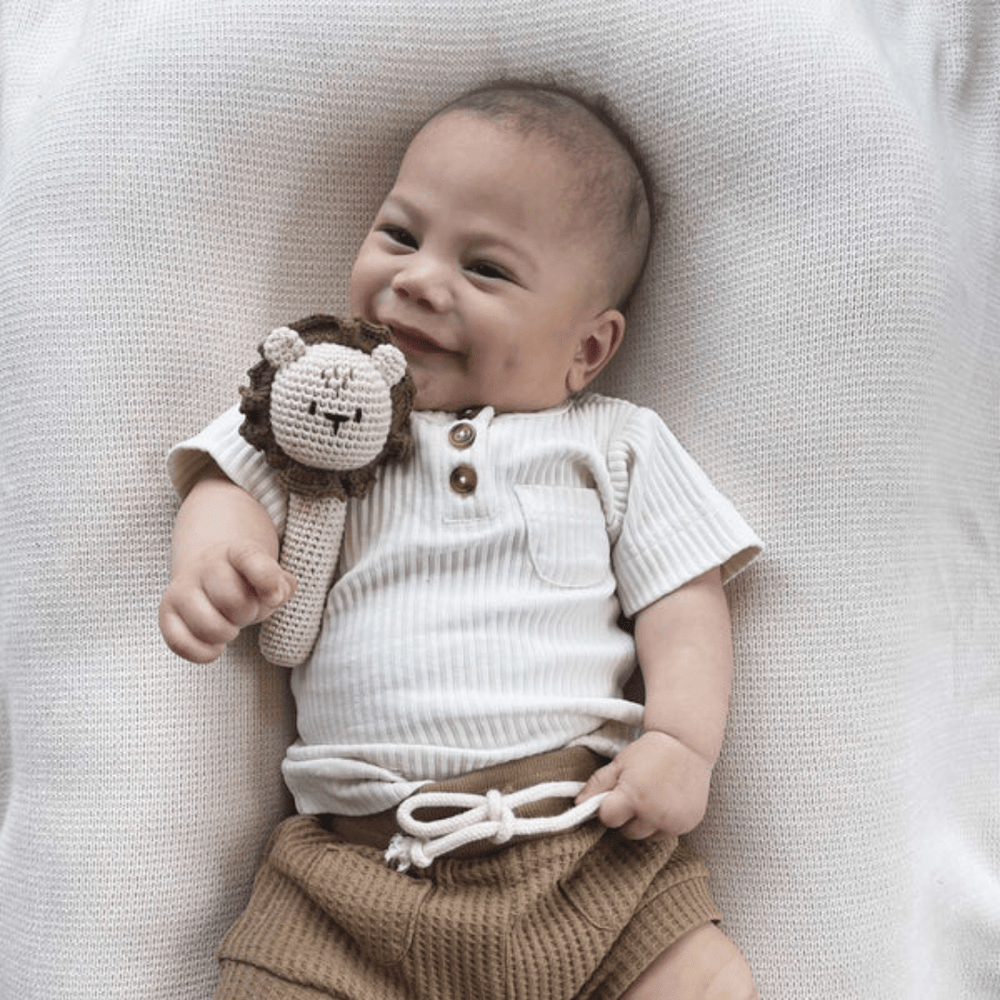 Happy-Baby-Holding-Over-The-Dandelions-Lion-Rattle-Naked-Baby-Eco-Boutique